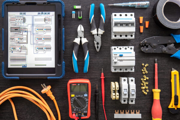 Flat lay composition with electrical tools and digital tablet on wooden background.